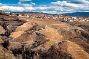 Panorama mozzafiato del paese piemontese con colline verdi e cieli azzurri.