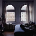 Immagine di una camera da letto con umidità visibile sulle pareti e un ventilatore acceso.