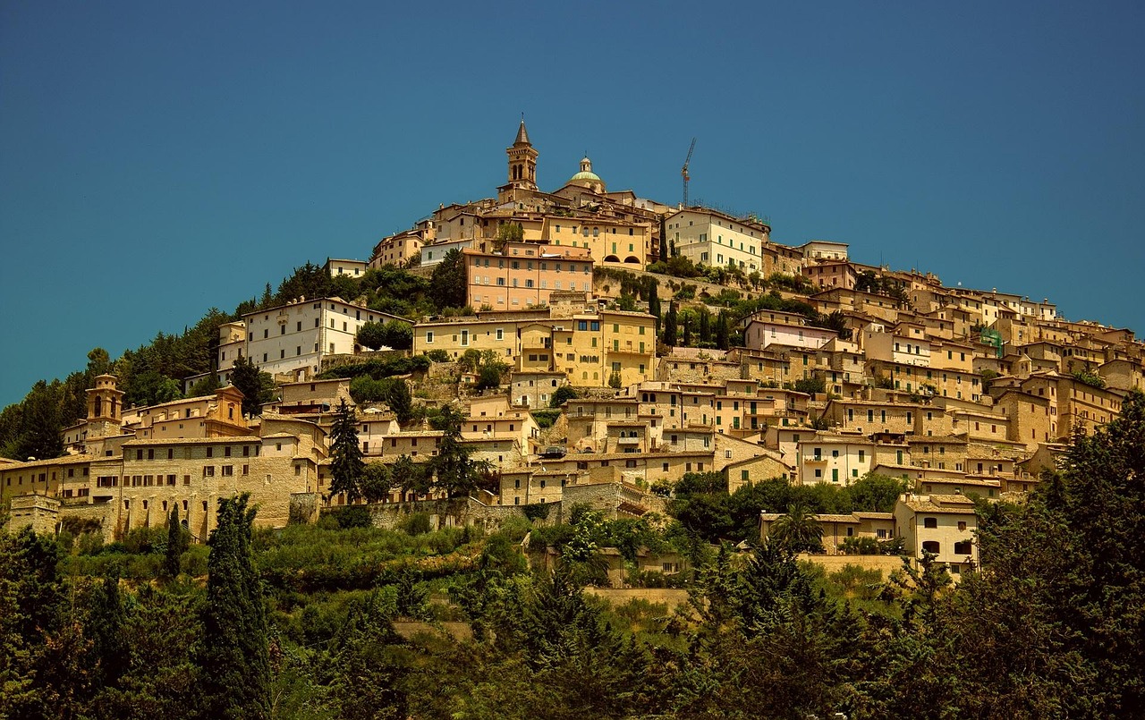 Panorama del paese caratteristico delle Marche, con antiche case in pietra e colline verdi sullo sfondo.